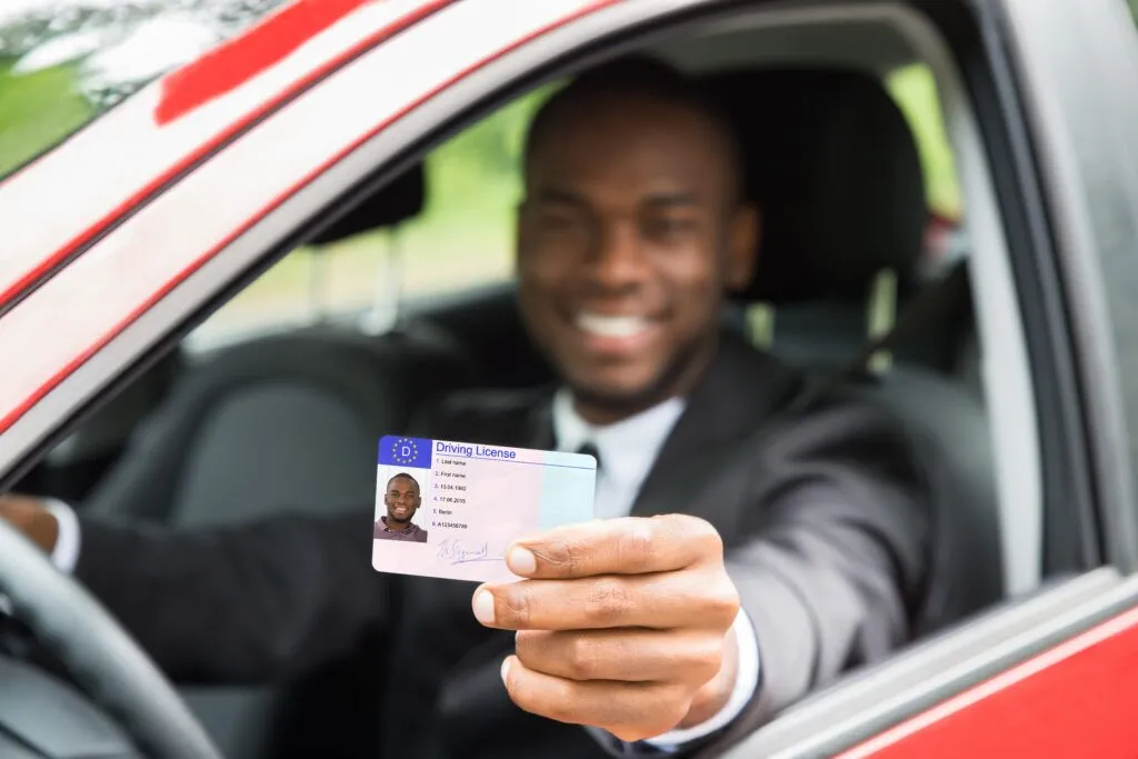 Driver license shown by man from open car window AdobeStock_116906731 1024x683 1